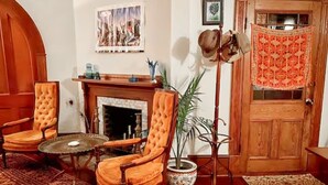 Un salón tradicional con chimenea, dos sillones, una mesa de centro y una planta en maceta.