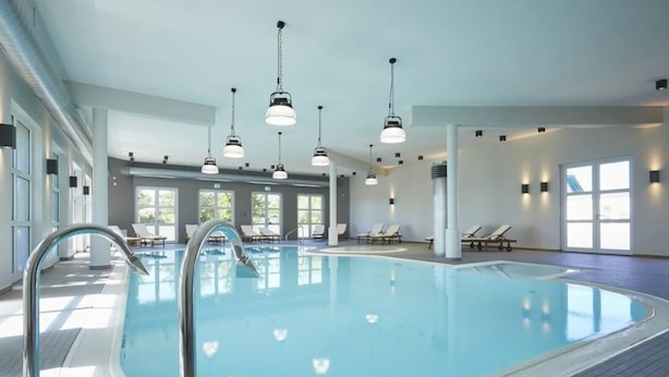 An indoor swimming pool with clear water, surrounded by lounge chairs and a tiled floor. - Comfy Apartment With Terrace (Dranske)