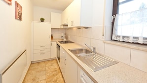 Una cocina compacta con armarios blancos, un lavamanos de acero inoxidable y un lavavajillas Bosch.