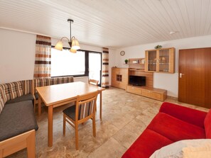 Una sala acogedora con una mesa de comedor de madera, un sofá rojo y un sofá a rayas.