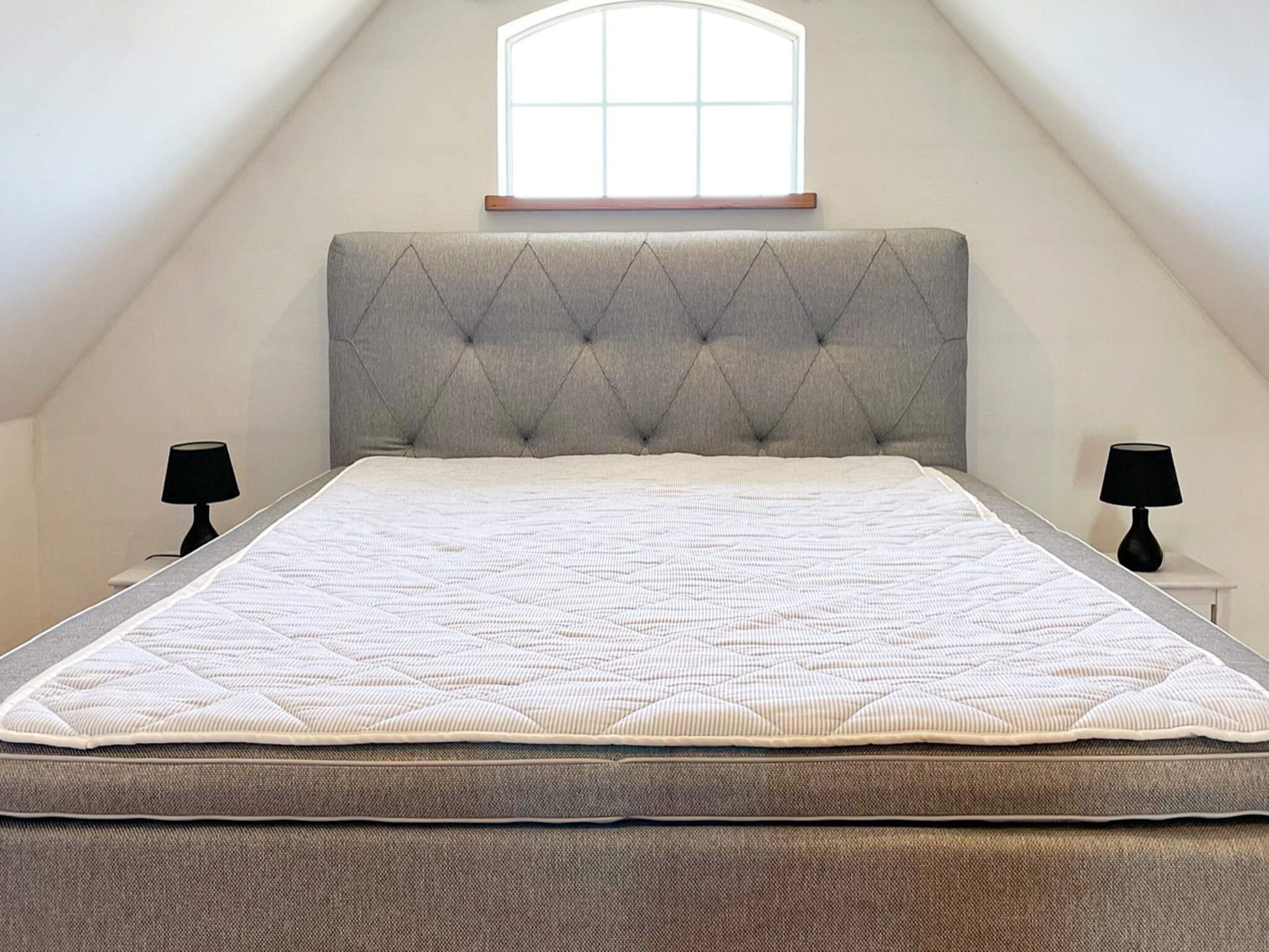 A bedroom with a large bed, a window, and two bedside lamps.