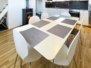 A modern kitchen with white cabinetry, a built-in stove, and a dining area with a white table and chairs. - 4 Star Holiday Home in Skivarp (Skivarp)