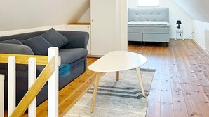 A loft-style room with a grey sofa, a white table, and a small rug. - 4 Star Holiday Home in Skivarp (Skivarp)