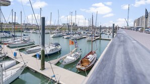 A marina with multiple boats docked, a walkway, and a building in the background. - Beachfront Holiday Home Near the Market (Blankenberge)