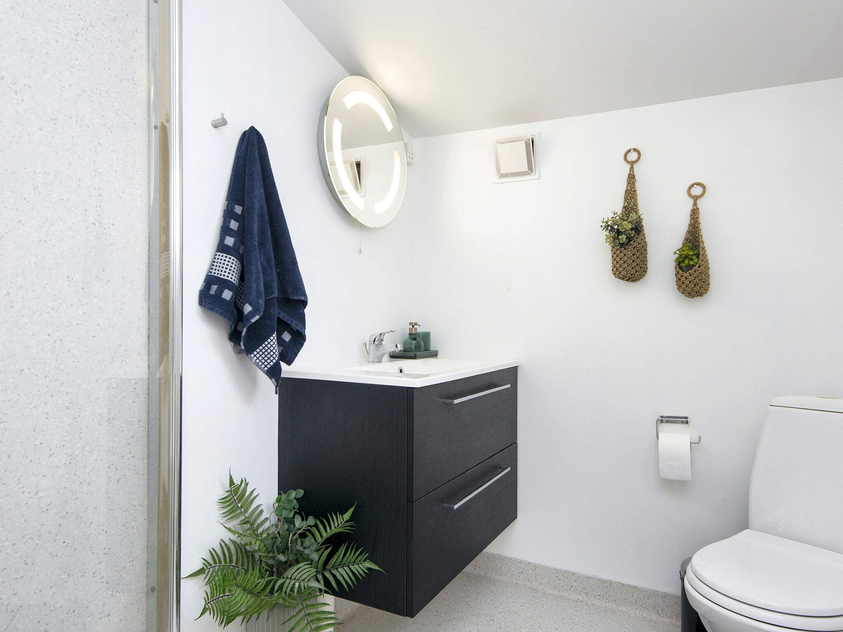Un baño moderno con un lavamanos blanco, un mueble oscuro y un inodoro.