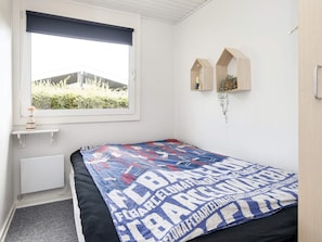 A bedroom with a bed, a window with a view of greenery, and two wall-mounted shelves with decorative items. - 8 Person Holiday Home in Aabenraa (Aabenraa)