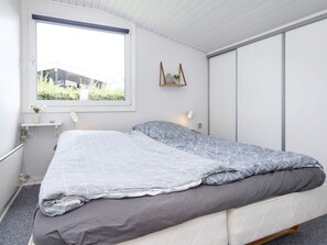A bedroom with a bed, a window, a bedside table, and a wall-mounted shelf. - 8 Person Holiday Home in Aabenraa (Aabenraa)