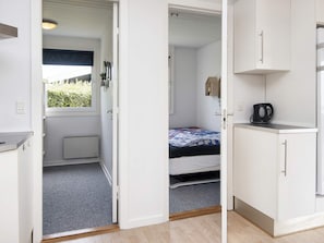 A compact room with a bed, a small kitchenette, and a window with a view of greenery. - 8 Person Holiday Home in Aabenraa (Aabenraa)