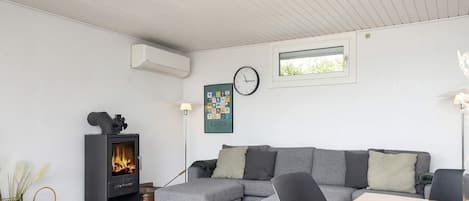Una sala de estar moderna con un sofá modular, una chimenea, un reloj y un cuadro en la pared.