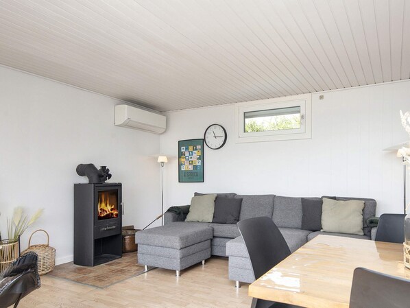A modern living room with a sectional sofa, a fireplace, a clock, and a framed picture on the wall.