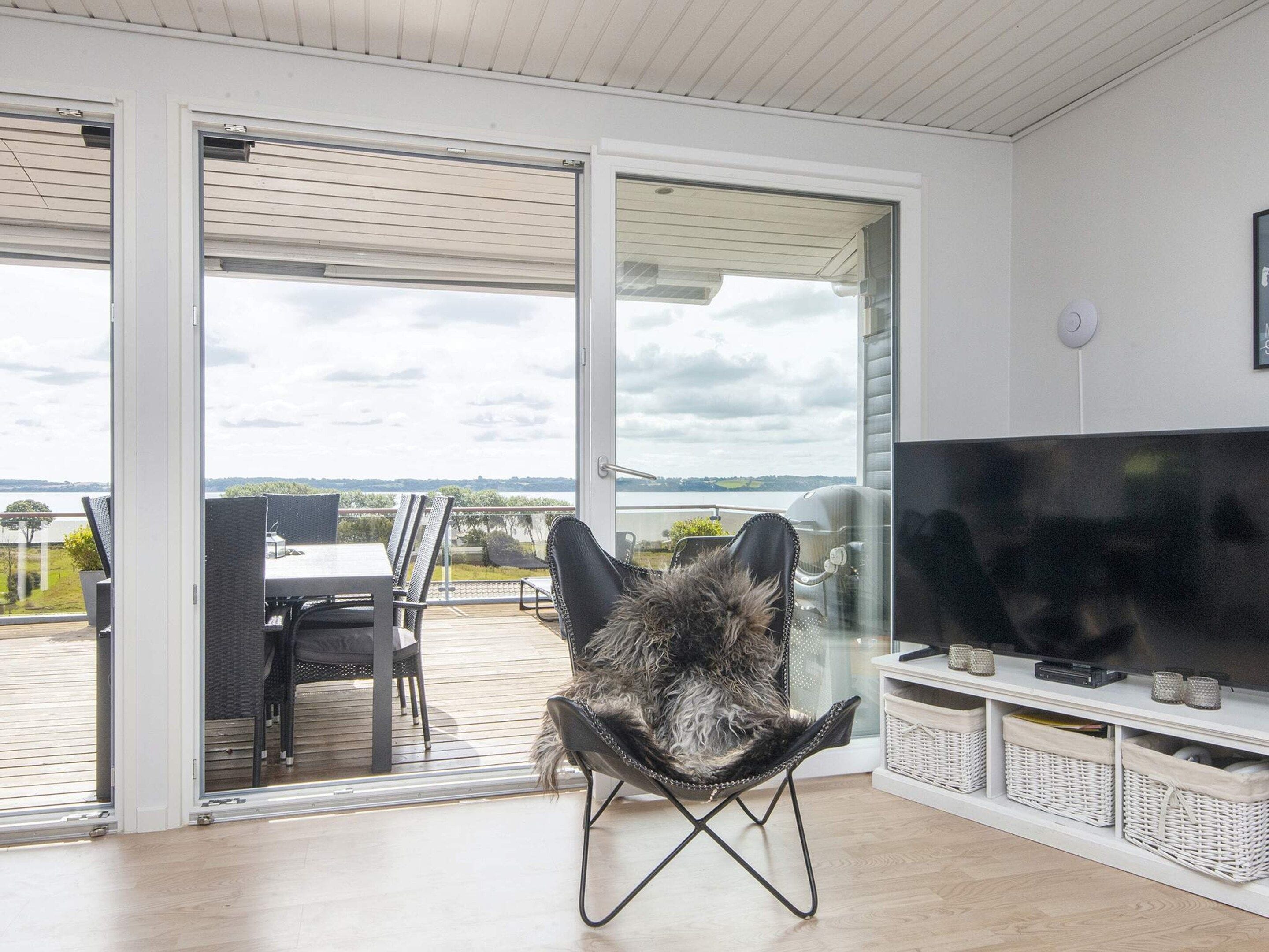 A modern living room with a large flat-screen TV, a comfortable chair, and a sliding glass door leading to an outdoor patio.