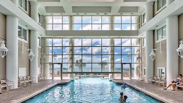 A large indoor swimming pool with a view of the ocean through large windows. - Beach Lovers Dream- 2 BR Majestic Sun Condo Sleeps 8! (Destin)