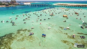 An aerial view of a coastal area with numerous boats, a pier, and a distant cityscape. - Beach Lovers Dream- 2 BR Majestic Sun Condo Sleeps 8! (Destin)