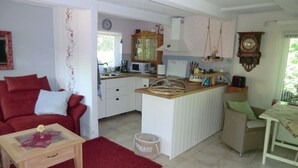 A compact living space with a kitchenette, a red sofa, a wooden coffee table, and a small dining area. - "min Hus" Quiet and Close to the Beach (Zingst)