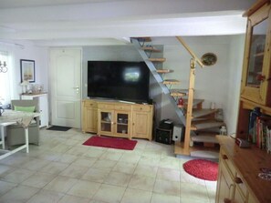 A living room with a TV, wooden cabinets, a red rug, and a staircase. - "min Hus" Quiet and Close to the Beach (Zingst)
