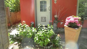 A house with a red exterior, a white door, and a small garden with various plants and flowers. - "min Hus" Quiet and Close to the Beach (Zingst)