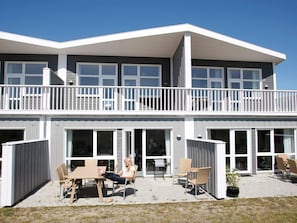 A two-story building with a balcony, large windows, and outdoor seating.