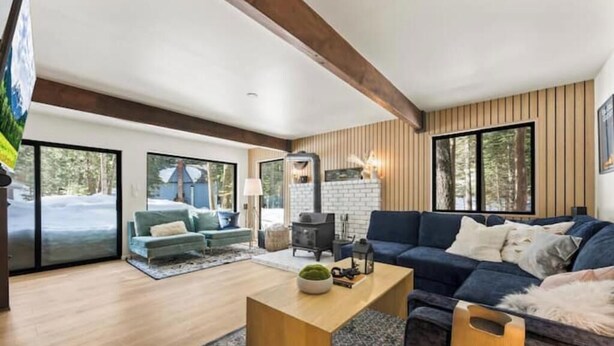 A modern living room with a fireplace, sofas, and a large window.
