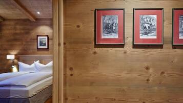 A wooden-paneled room with a bed, a nightstand, and three framed pictures on the wall.