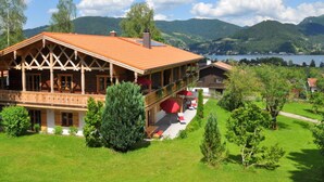 A wooden chalet with a balcony, surrounded by lush greenery and a lake view. - Suite Birch Modern Retreat (Bad Wiessee)