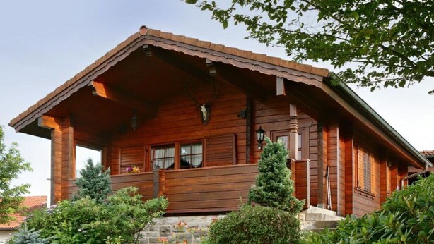 A wooden cabin with a sloped roof, a porch with a railing, and a stone foundation. - Holiday Home Anja in Motten (Motten)