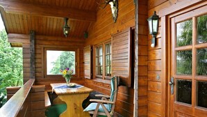 A wooden cabin with a covered porch, a dining table, and a chair. - Holiday Home Anja in Motten (Motten)