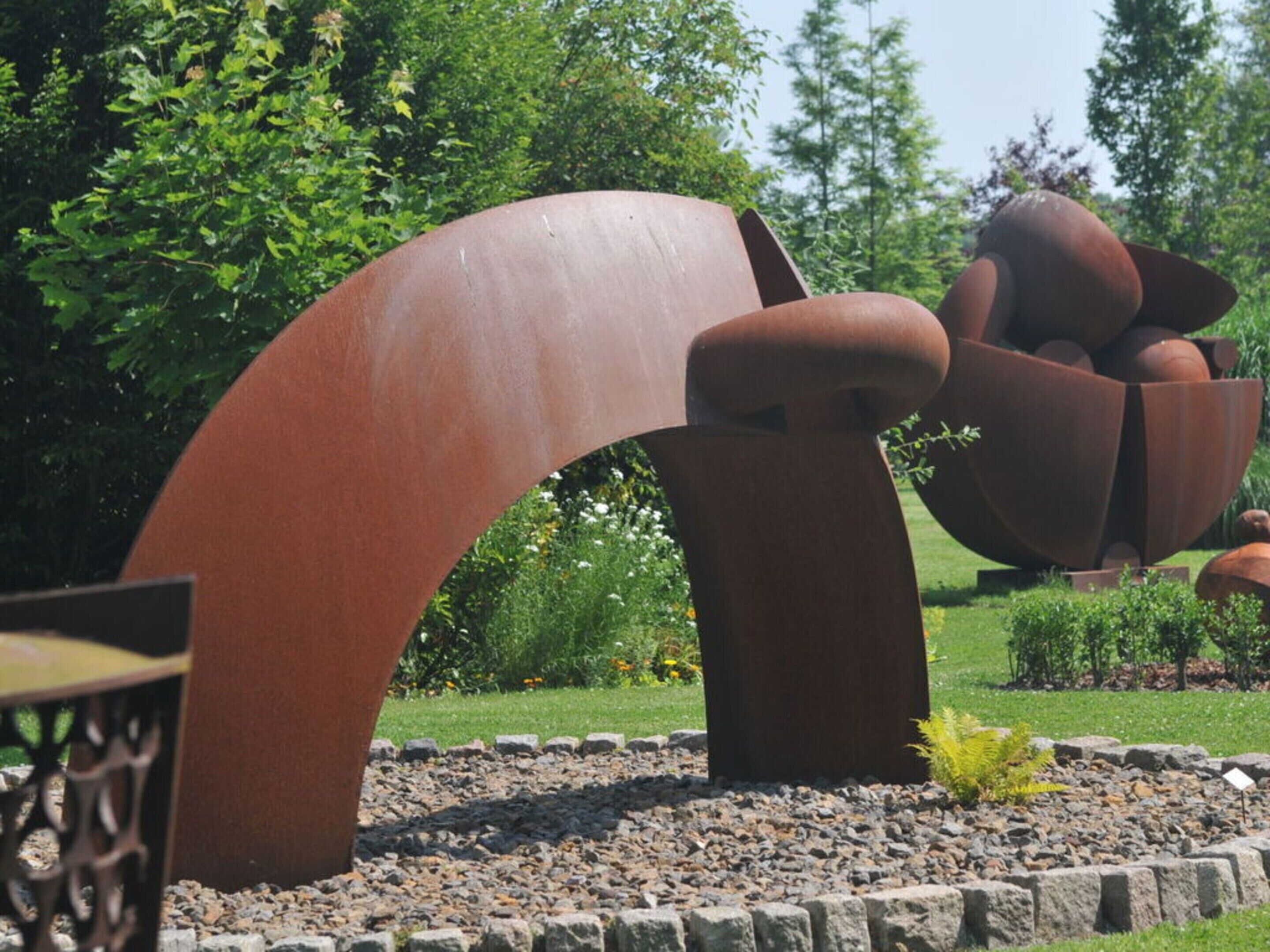 A sculpture garden with abstract metal structures and a paved pathway.