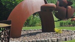Un jardin de sculptures présentant des structures métalliques abstraites et un sentier dallé.