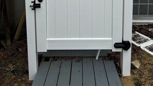 A white wooden gate with black hardware, set against a house with gray siding and a window. - Last minute Cape cod rental
  Bikes,  Beach ,ac  ,laundry ,ping pong table  (Dennis)