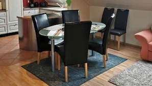 A modern kitchen with skylights, a dining area with chairs, and a small seating area with a pink chair. - "haus Burck" Modern Retreat (Wankendorf)