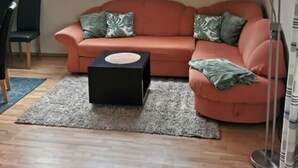 A cozy living room with a pink sofa, a black ottoman, and a skylight with three windows. - "haus Burck" Modern Retreat (Wankendorf)