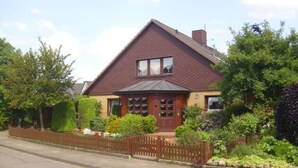 A two-story house with a brown roof, a front porch, and a wooden fence. - "haus Burck" Modern Retreat (Wankendorf)