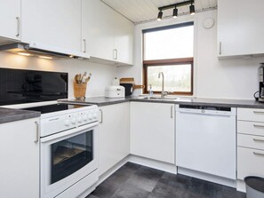 A modern kitchen with white cabinetry, a built-in oven, a dishwasher, and a window providing natural light. - 6 Person Holiday Home in Hemmet (Hemmet)