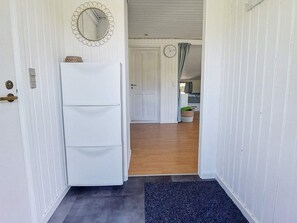 A hallway with a white door, a mirror, and a clock on the wall.