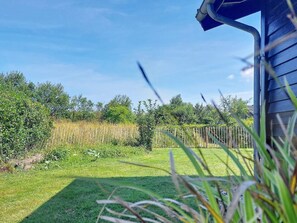 A grassy yard with a wooden fence and a house with a blue exterior. - 6 Person Holiday Home in Hemmet (Hemmet)