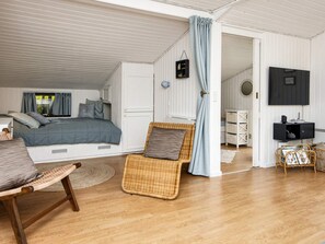 A bedroom with a bed, a chair, a TV, and a wardrobe.