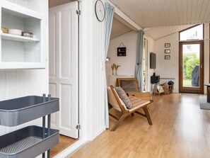 A room with a wooden floor, a wicker chair, a white door, and a view of the outdoors. - 6 Person Holiday Home in Hemmet (Hemmet)