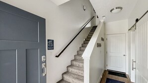 Un escalier muni d’une rampe, un tapis bleu au bas et une porte avec une enseigne au-dessus.