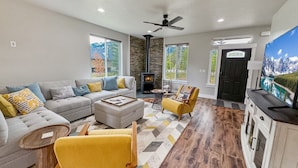 A modern living room with a sofa, armchairs, a coffee table, and a fireplace. - Stunning Home Close to Lake Cascade (Donnelly)