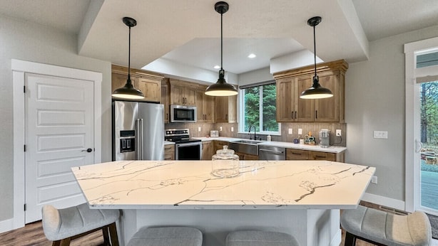 A kitchen with a large island, wooden cabinets, and pendant lighting. - Stunning Home Close to Lake Cascade (Donnelly)