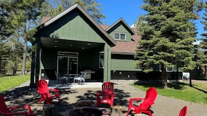 A lodge with a green exterior, a fire pit, and red Adirondack chairs. - Stunning Home Close to Lake Cascade (Donnelly)