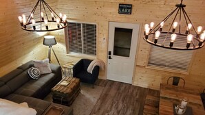 L’intérieur d’un chalet accueillant, avec un canapé, un fauteuil et une table à manger.
