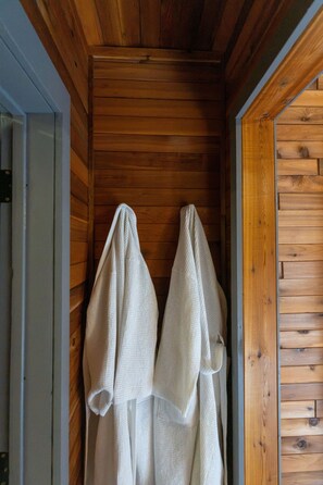 A wooden interior with two white robes hanging on a rack. - Ultimate vacation lodge (Gimli)