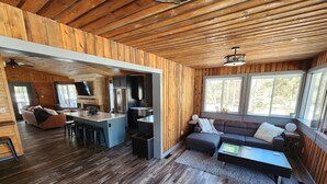 Een modern cabin interieur met houten details, een keukenhoek, een zithoek met een bank en salontafel, en grote ramen die voor natuurlijk licht zorgen.