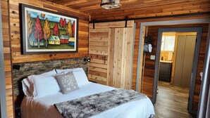 Een slaapkamer in blokhutstijl met een bed, een schilderij en een houten plafond.