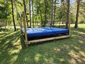 Un cadre de lit en bois avec un matelas bleu, situé dans une zone boisée.