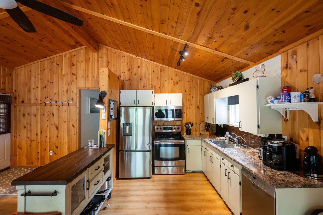 Une cuisine avec des murs en bois, des appareils électroménagers en acier inoxydable et un plan de travail en granit.