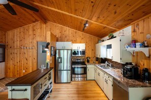 A kitchen with wooden walls, stainless steel appliances, and a granite countertop.