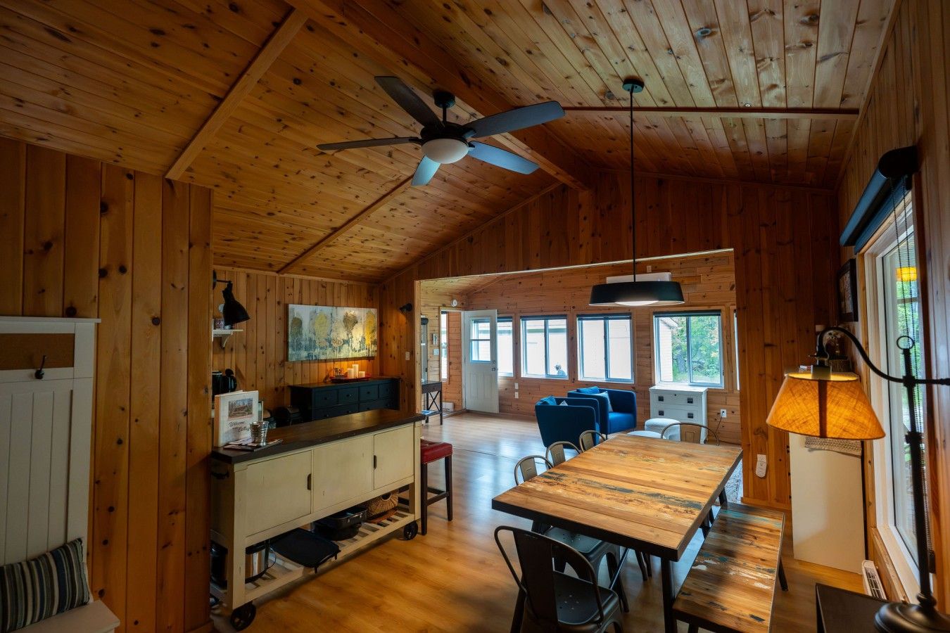 Un intérieur en bois comprenant un coin repas, une cuisine et un ventilateur de plafond.