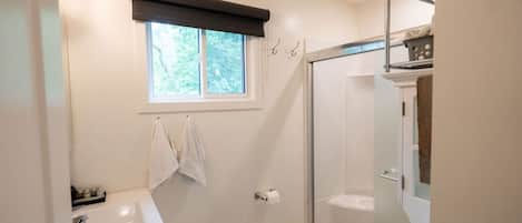 A bathroom with a bathtub, a shower, and a window.